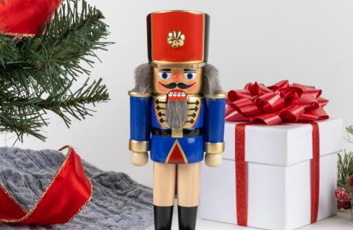 Soldier nutcracker standing by tree and gift box