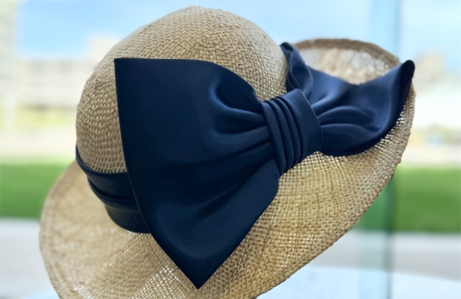 Straw Hat wth Navy blue bow on stand, outside grass in background