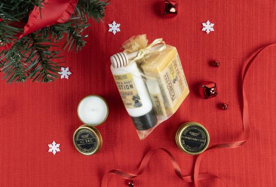 two small candles and gift pack with lotion, soap, balm and honey dipper