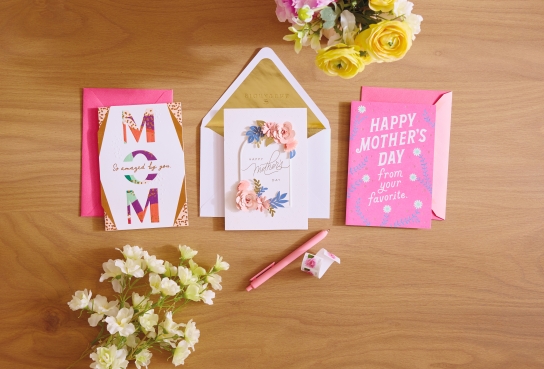 Greeting cards on wooden table top, with flowers nearby