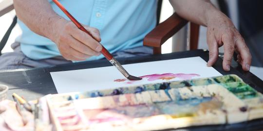 Hands of artist painting with water colors