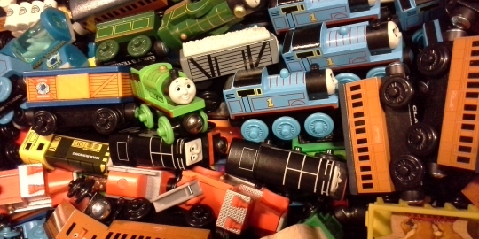 Pile of train cars feature characters from Thomas and Friends in blue, orange, green