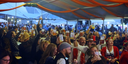 People toasting with beer mugs under pavilion